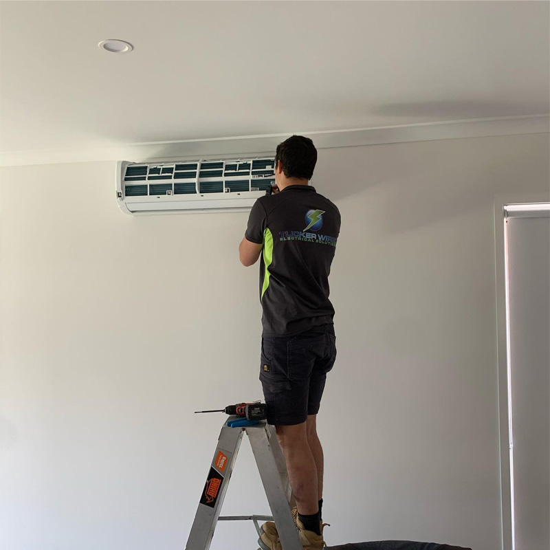 Technician on a stepladder working on a wall-mounted split system