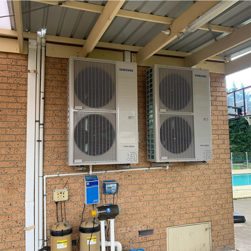 Two large Samsung outdoor units on a brick wall under a pergola